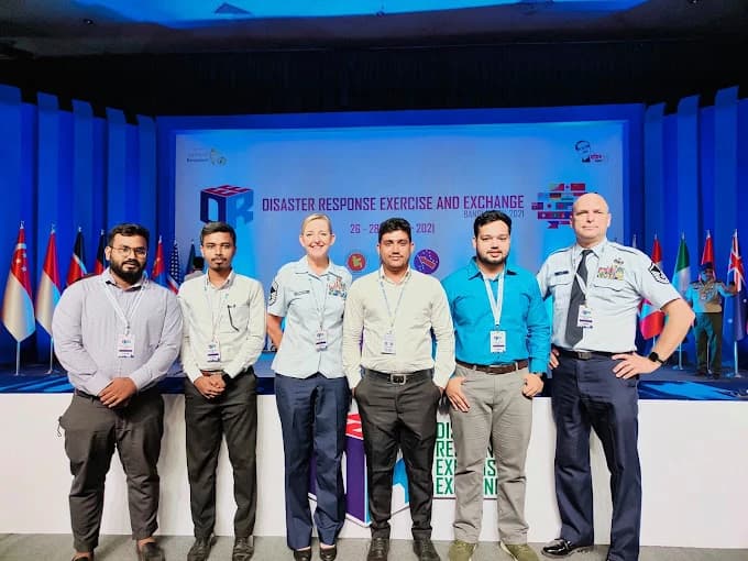 Six people standing together in front of a conference stage